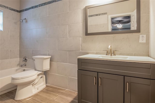 full bathroom featuring vanity, wood-type flooring, tile walls, toilet, and tiled shower / bath