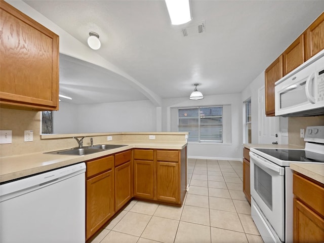 kitchen with light tile patterned flooring, sink, white appliances, and kitchen peninsula