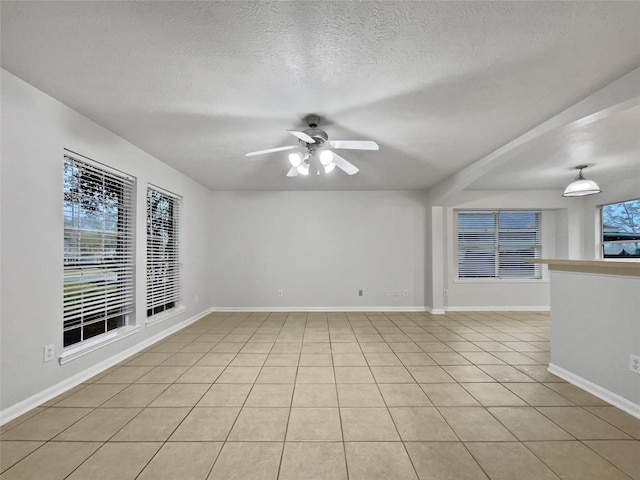 unfurnished room featuring plenty of natural light, ceiling fan, light tile patterned floors, and a textured ceiling