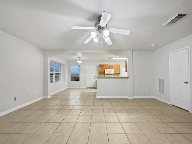 unfurnished living room featuring ceiling fan, light tile patterned flooring, and a textured ceiling