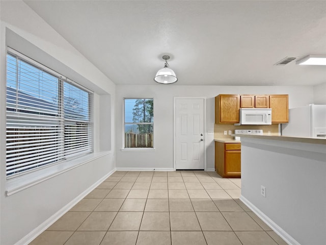 kitchen featuring light tile patterned floors, white appliances, and pendant lighting