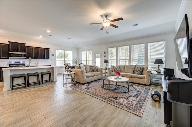 living room featuring light hardwood / wood-style floors, ceiling fan, and crown molding