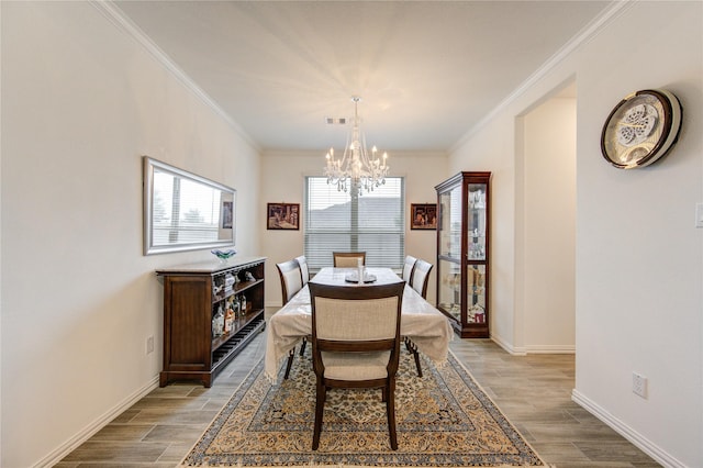 dining room featuring a chandelier, light hardwood / wood-style floors, and crown molding