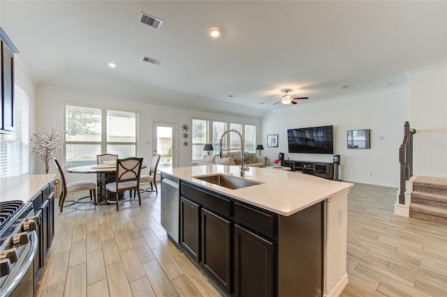 kitchen featuring a center island with sink, sink, light hardwood / wood-style flooring, ceiling fan, and stainless steel appliances