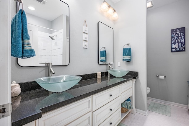 bathroom with tiled shower, vanity, and toilet