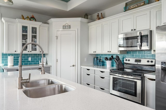 kitchen featuring decorative backsplash, sink, white cabinets, and stainless steel appliances