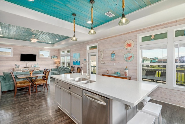 kitchen with dishwasher, pendant lighting, sink, and wood walls