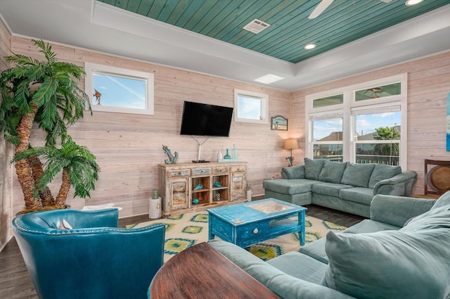 living room featuring hardwood / wood-style floors, plenty of natural light, a raised ceiling, and wooden walls