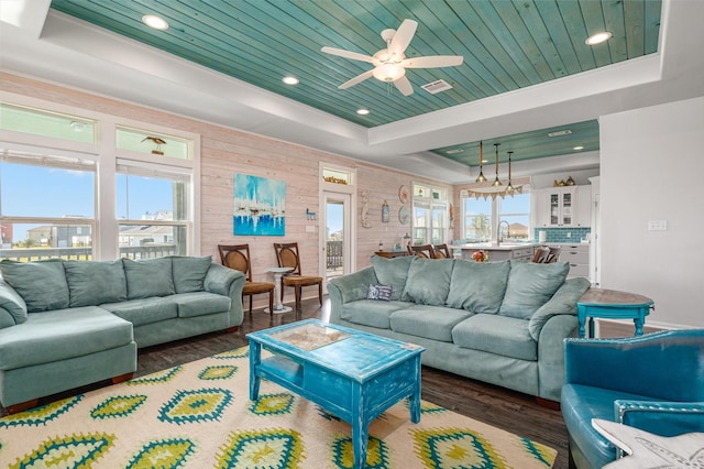 living room with a tray ceiling, ceiling fan, sink, wooden ceiling, and dark hardwood / wood-style floors