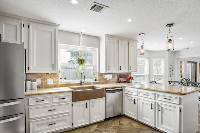 kitchen with stainless steel appliances, white cabinetry, and a healthy amount of sunlight