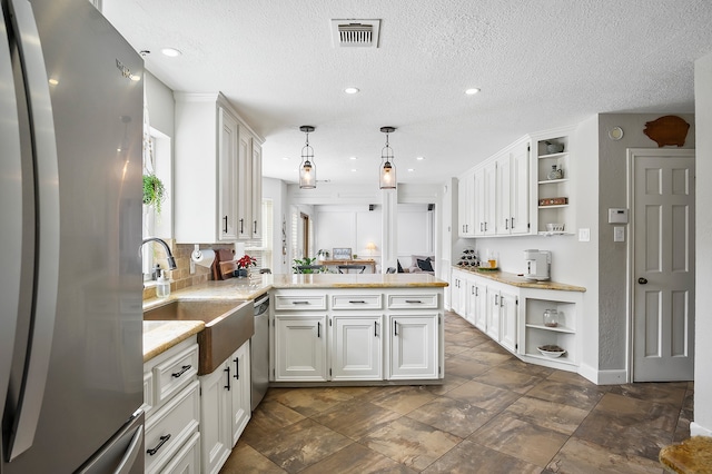 kitchen featuring white cabinetry, hanging light fixtures, stainless steel appliances, kitchen peninsula, and a textured ceiling