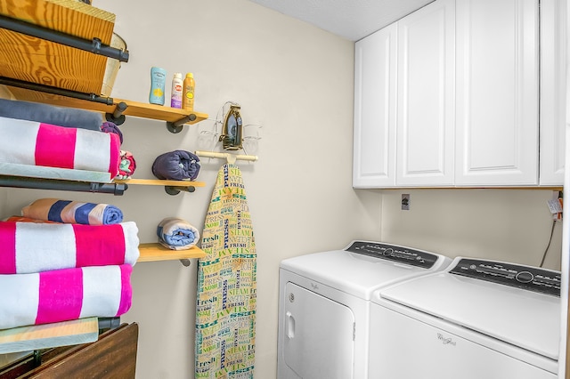 clothes washing area featuring cabinets and separate washer and dryer