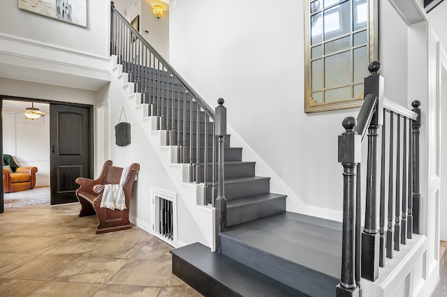 stairs featuring a high ceiling and ceiling fan