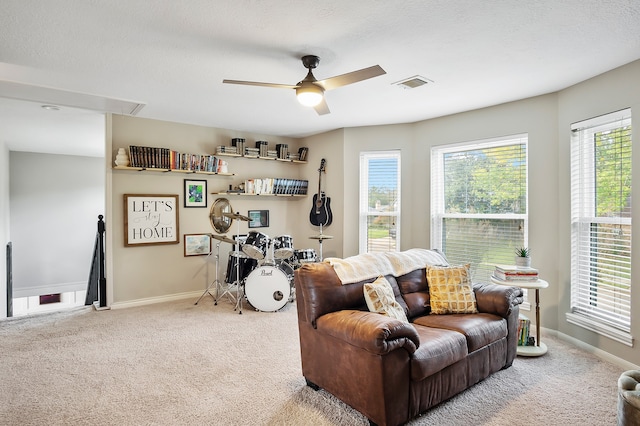 living room featuring carpet, a textured ceiling, ceiling fan, and a healthy amount of sunlight