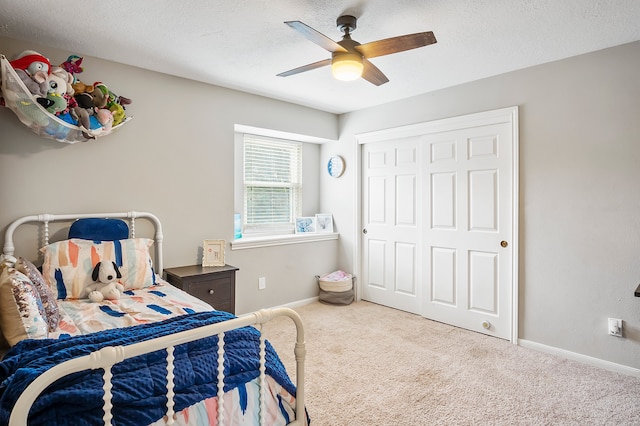 carpeted bedroom featuring ceiling fan, a textured ceiling, and a closet