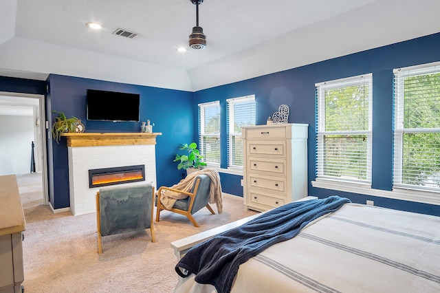 bedroom with ceiling fan, vaulted ceiling, light colored carpet, and a brick fireplace