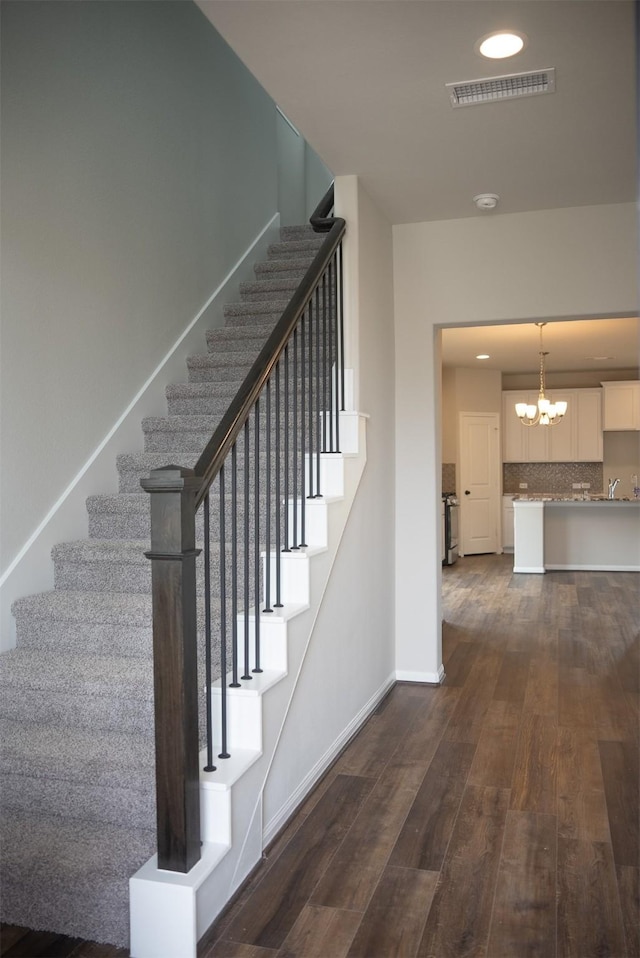 stairway with a chandelier and wood-type flooring