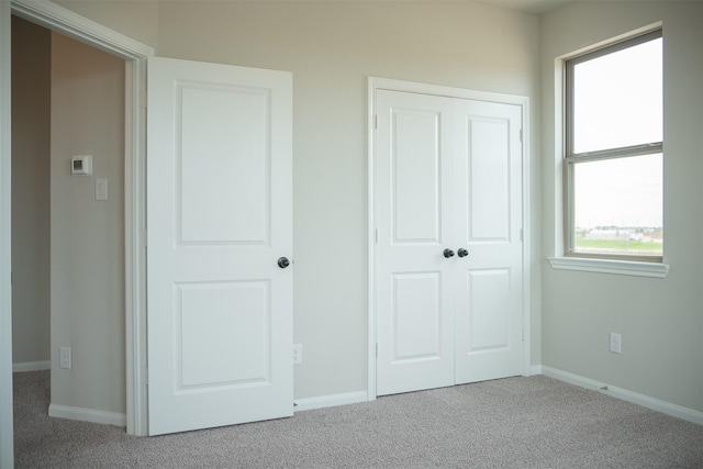 unfurnished bedroom with light carpet and a closet