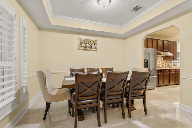 7411 Shady Arbour Ct, Pasadena, TX 77505 - dining room featuring ornamental molding, a textured ceiling, arched walkways, and a tray ceiling