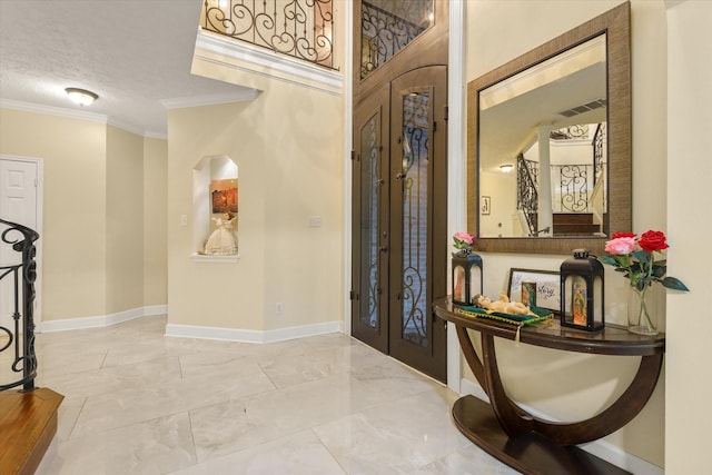 foyer with french doors, a textured ceiling, and ornamental molding