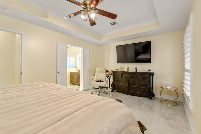 bedroom with ceiling fan, ornamental molding, ensuite bathroom, and a tray ceiling