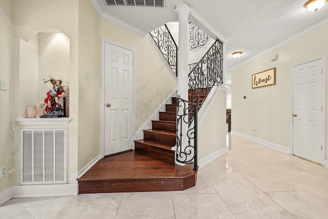 staircase with wood-type flooring, a textured ceiling, ornate columns, and ornamental molding