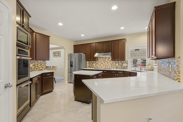 kitchen with kitchen peninsula, stainless steel appliances, tasteful backsplash, and sink