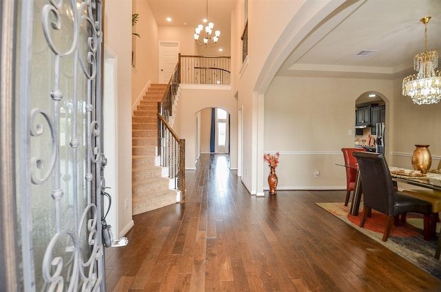 foyer with a high ceiling, dark hardwood / wood-style floors, and an inviting chandelier