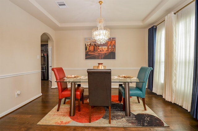 dining room with a tray ceiling, a chandelier, and dark hardwood / wood-style floors