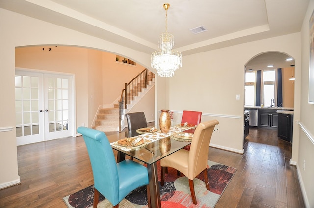 dining space with french doors, a tray ceiling, sink, a notable chandelier, and dark hardwood / wood-style floors