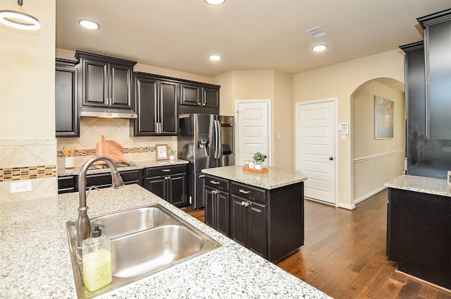 kitchen with a center island, sink, stainless steel refrigerator with ice dispenser, light stone countertops, and dark hardwood / wood-style flooring