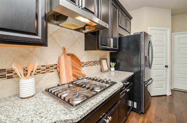 kitchen featuring light stone countertops, tasteful backsplash, dark hardwood / wood-style flooring, dark brown cabinetry, and stainless steel appliances