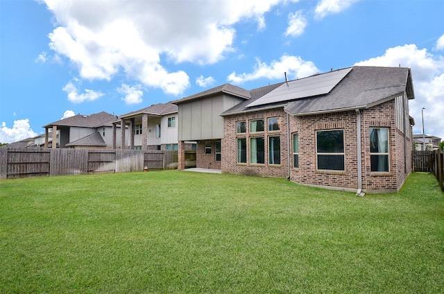 back of property featuring solar panels and a yard