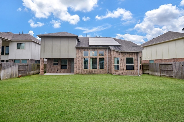 back of house featuring solar panels and a yard