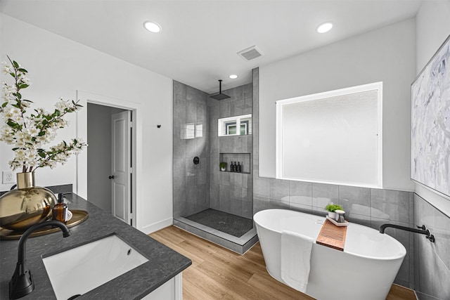 bathroom with hardwood / wood-style flooring, tile walls, separate shower and tub, and vanity