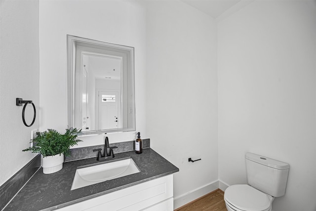 bathroom with toilet, vanity, and wood-type flooring