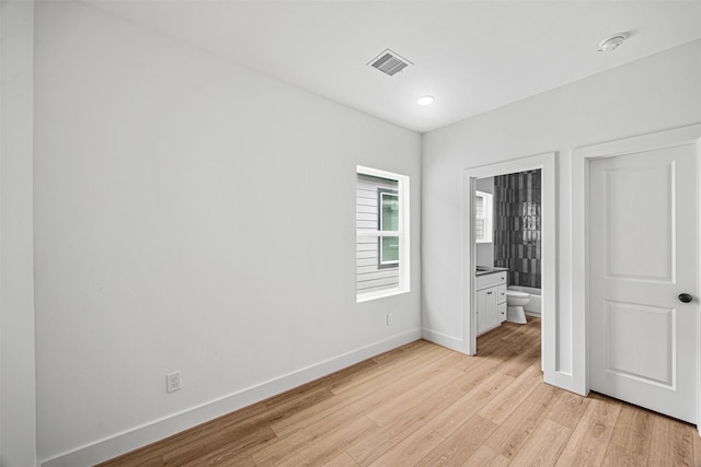 unfurnished bedroom with connected bathroom and light hardwood / wood-style floors