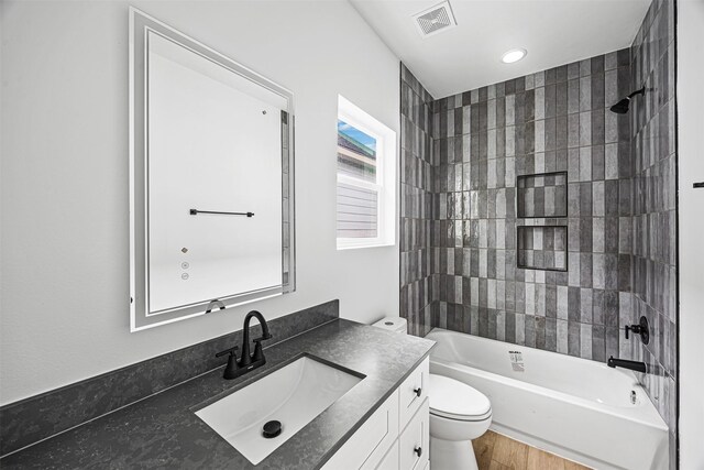 full bathroom featuring toilet, tiled shower / bath combo, and vanity