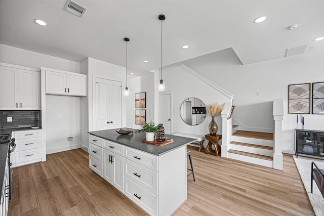 kitchen with white cabinetry, a breakfast bar area, backsplash, decorative light fixtures, and a center island