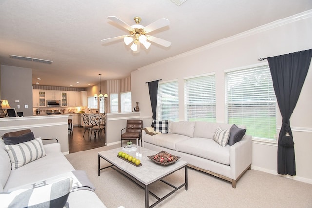 living room with a wealth of natural light, ceiling fan with notable chandelier, and ornamental molding