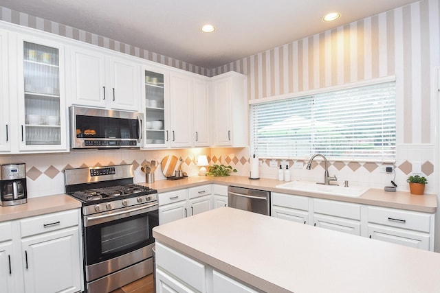 kitchen featuring tasteful backsplash, white cabinets, appliances with stainless steel finishes, and sink