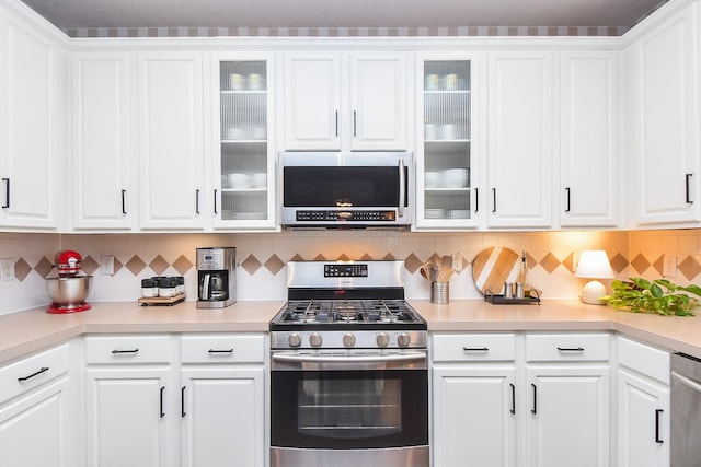 kitchen featuring decorative backsplash, white cabinets, and stainless steel appliances