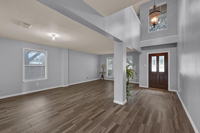 entrance foyer with a towering ceiling, a textured ceiling, and dark hardwood / wood-style flooring