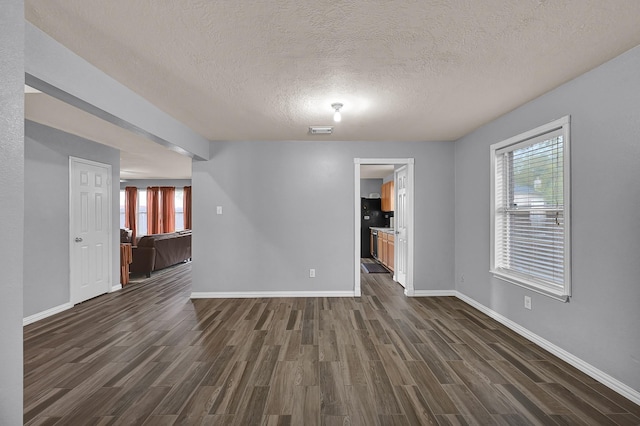 empty room with a textured ceiling and dark hardwood / wood-style floors