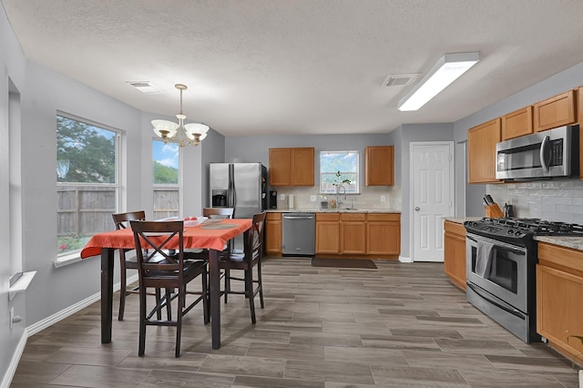 kitchen featuring decorative backsplash, appliances with stainless steel finishes, decorative light fixtures, and a notable chandelier