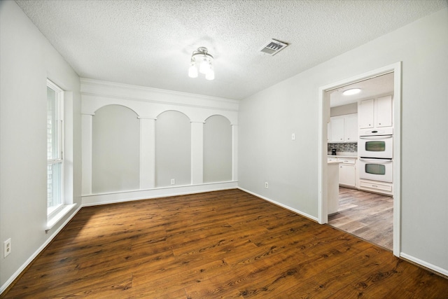 unfurnished room with a textured ceiling and dark hardwood / wood-style flooring