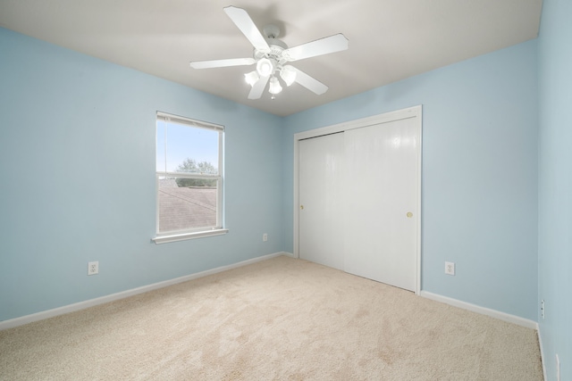 unfurnished bedroom with ceiling fan, light carpet, and a closet