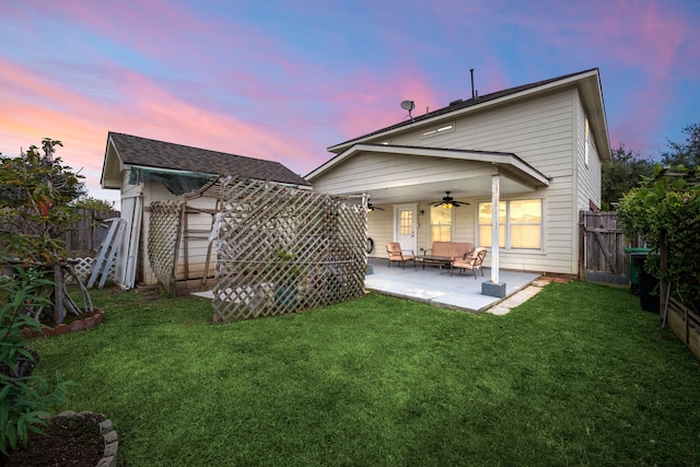 back house at dusk with a lawn, a patio area, and ceiling fan