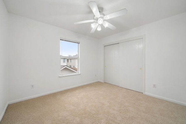 unfurnished bedroom featuring a closet, light colored carpet, and ceiling fan