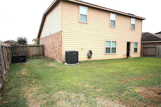 rear view of property with central air condition unit and a lawn